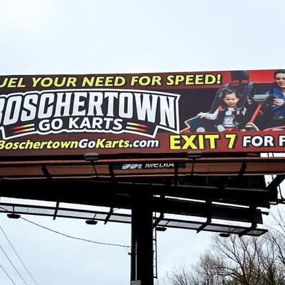 A billboard advertises Boschertown Go Karts in St. Charles with the slogan “Fuel your need for speed!” It shows a child and adult riding go karts, and includes the website and “Exit 7 for fun.”.